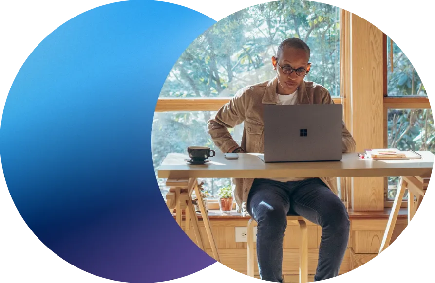 middle aged man with glasses on laptop managing domains while sitting at wooden desk by windows