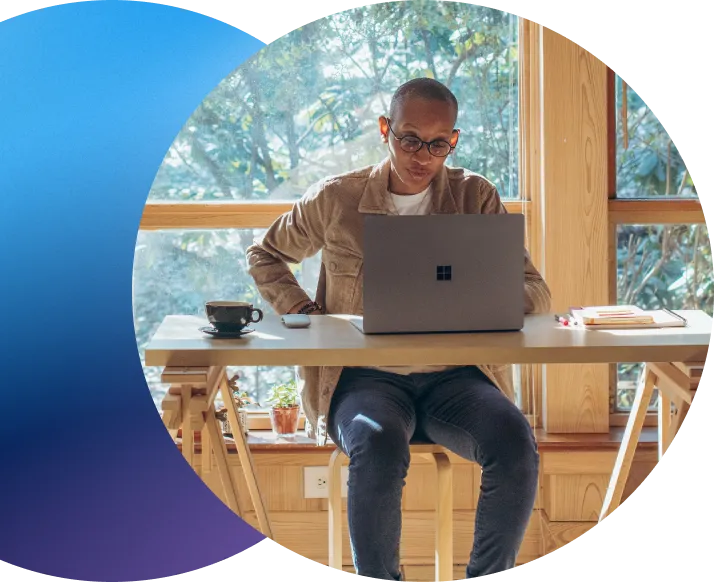 middle aged man with glasses on laptop managing domains while sitting at wooden desk by windows